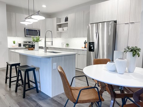 A modern kitchen with a white table and chairs.